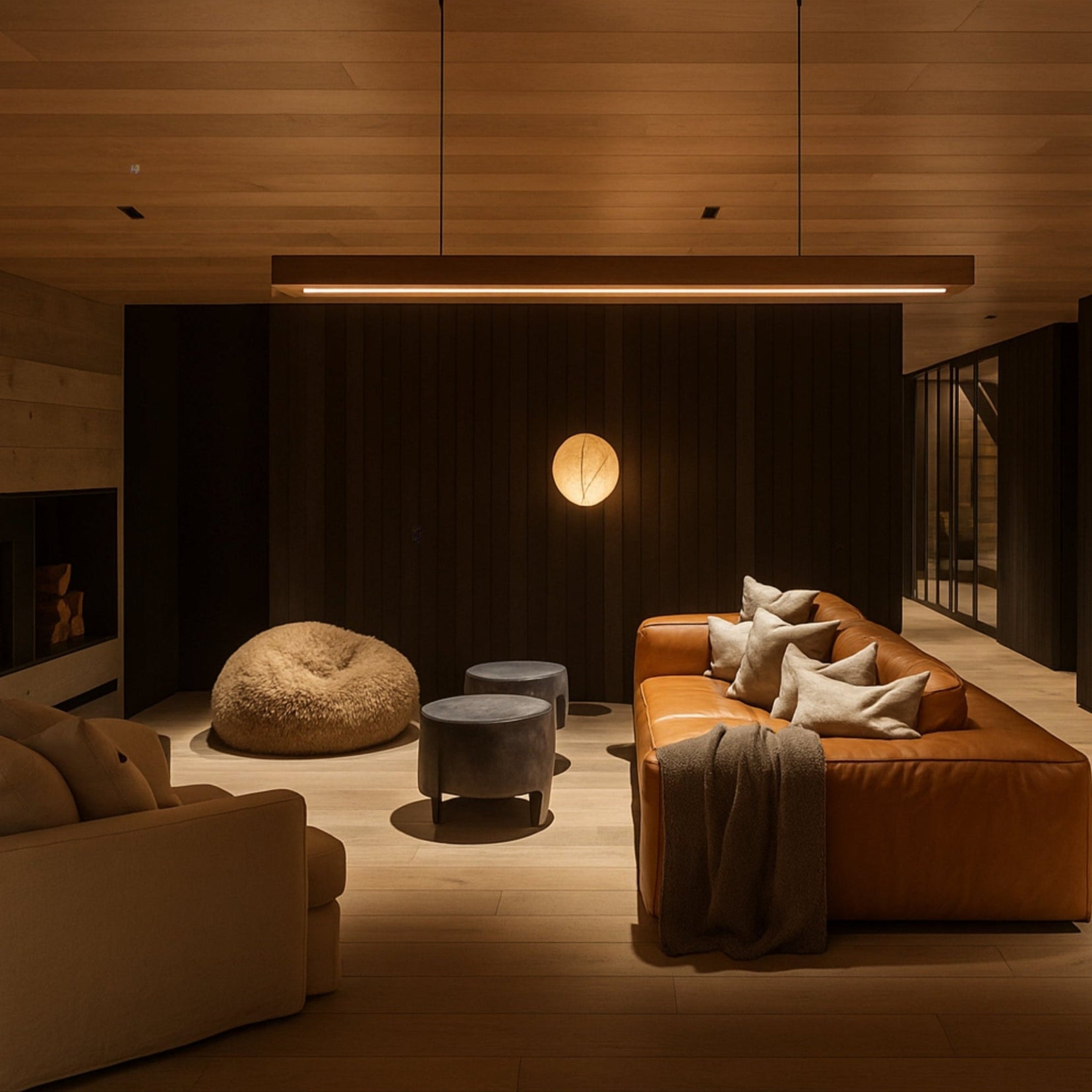 Modern living room with brown leather sofa, ottoman, and pendant light.