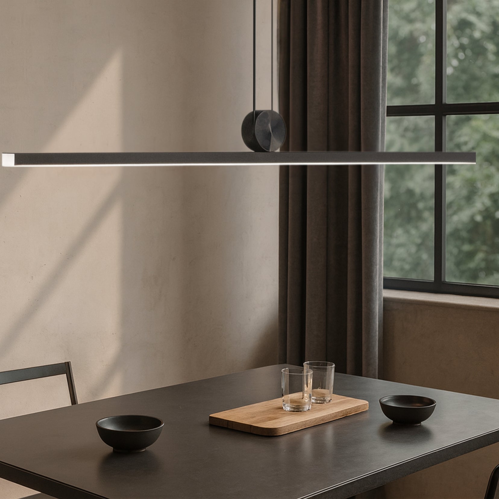 Chord pendant light by Love Hohm hanging above a dining table with minimal decor.