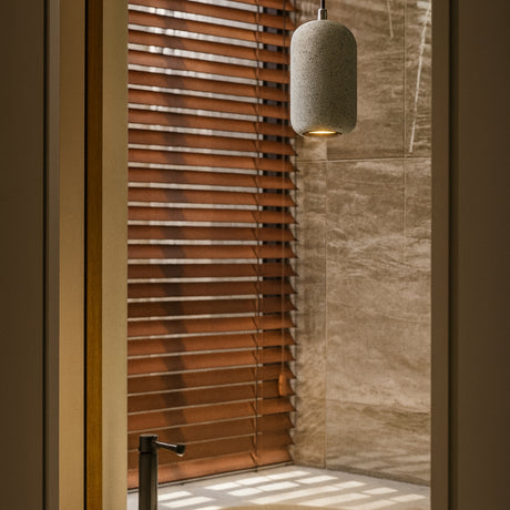 Shower area with wooden blinds and a hanging light fixture.