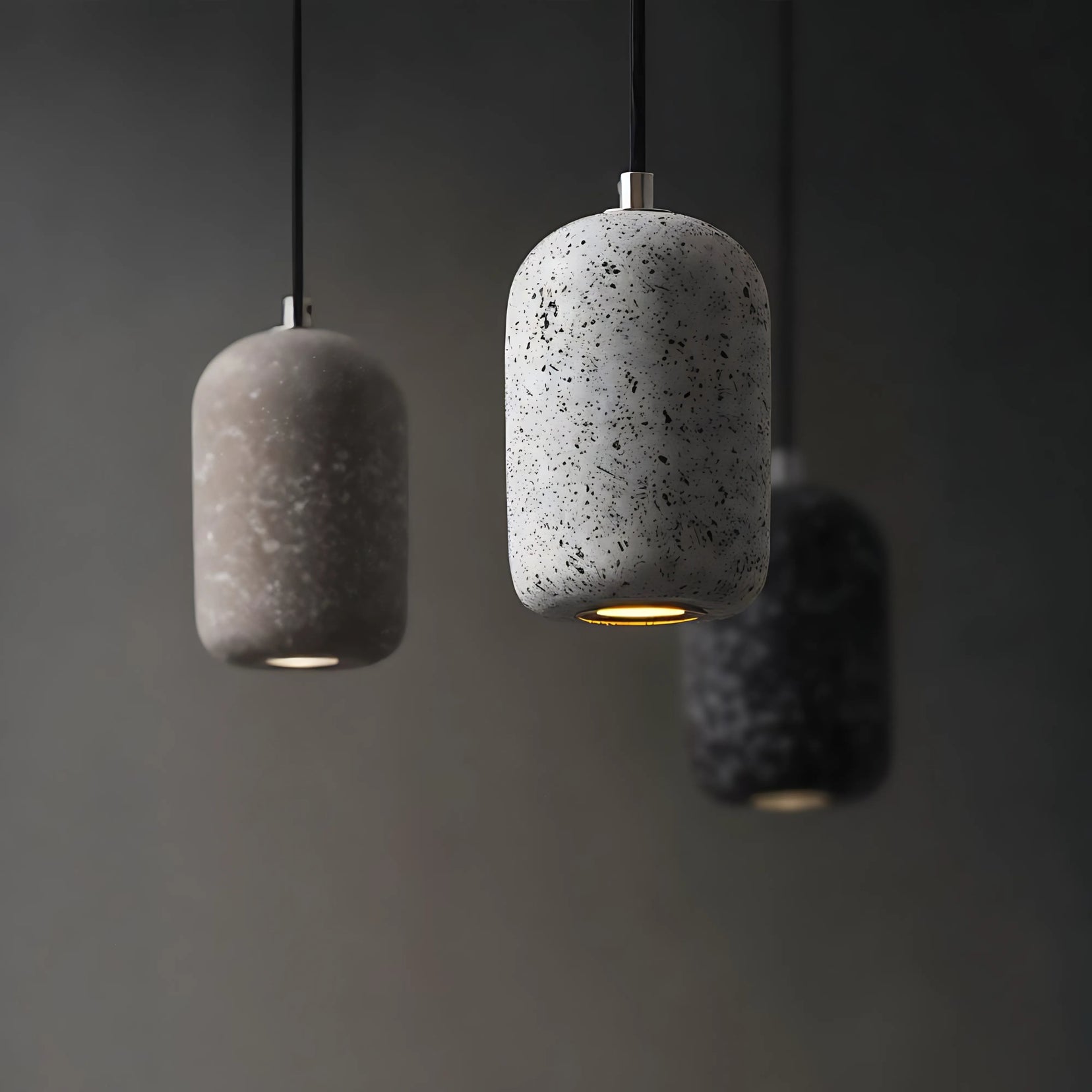 Three concrete pendant lights hanging against a dark background
