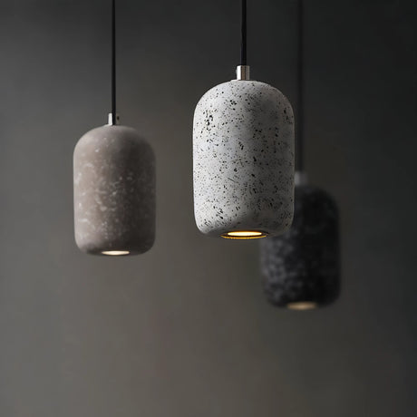 Three concrete pendant lights hanging against a dark background