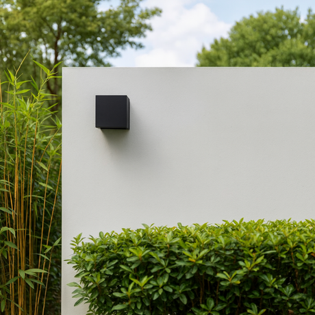 Dune outdoor wall lamp from Love Hohm on a white wall with greenery in the background