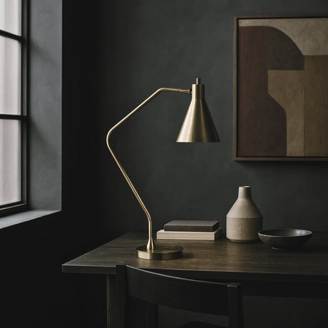 Formant desk lamp from Love Hohm on a dark wooden desk with decor items against a dark wall.