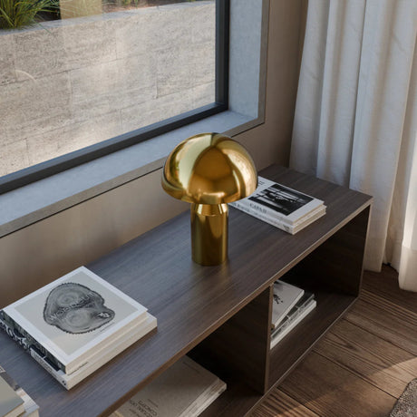 Gold lamp on a wooden shelf with books in a modern interior setting