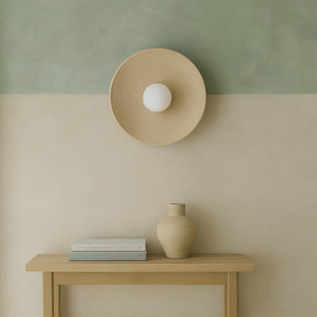 Groove wall light from Love Hohm above a wooden console table with a vase and books against a two-tone wall.
