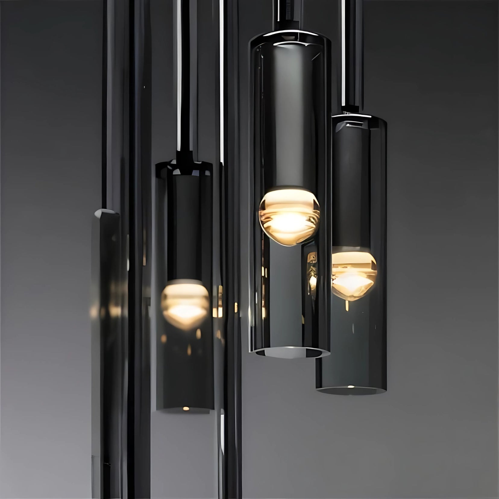 Modern Loom pendant light from Love Hohm with black cylindrical fixture and glass cover on a dark background