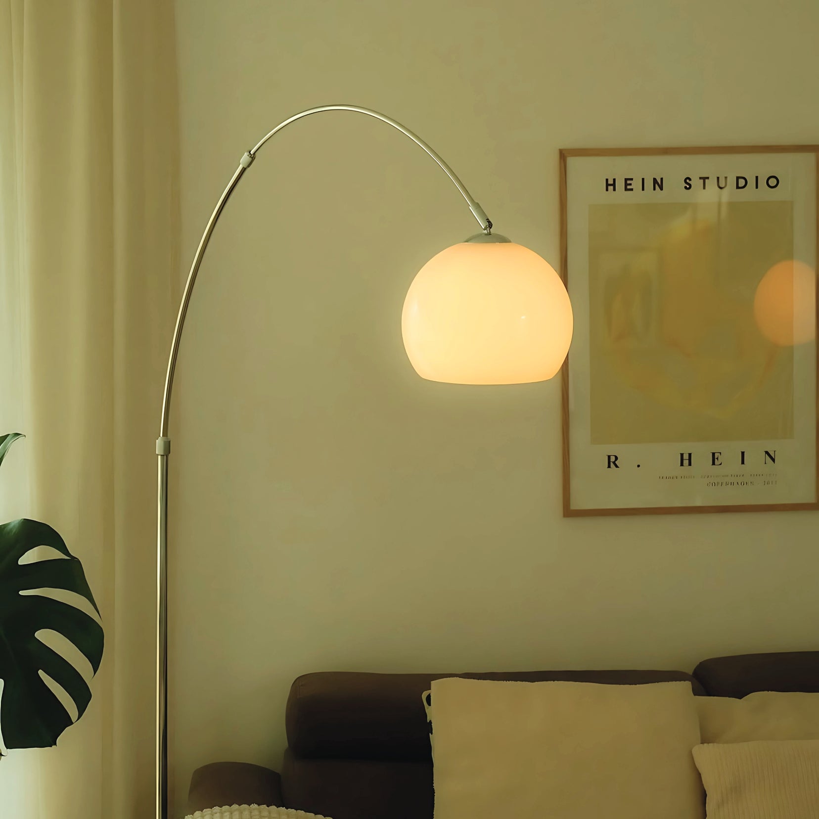 Overture arc floor lamp from Love Hohm with a round shade in a living room setting, featuring a poster on the wall.