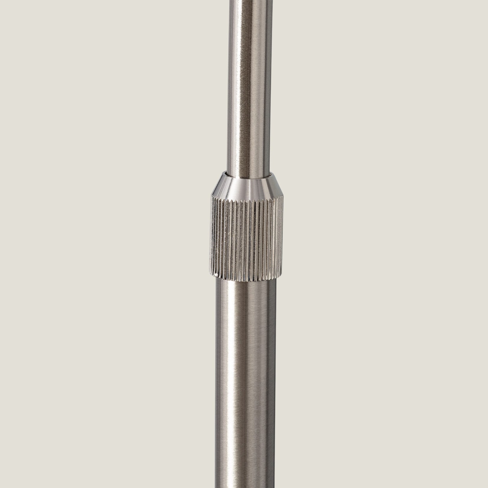 Overture arch floor lamp close-up of a metallic pole with a textured grip on a light gray background