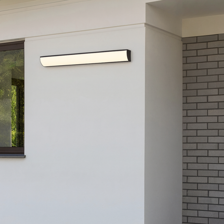 Quill outdoor wall lamp from Love Hohm on a white wall with a brick pattern.