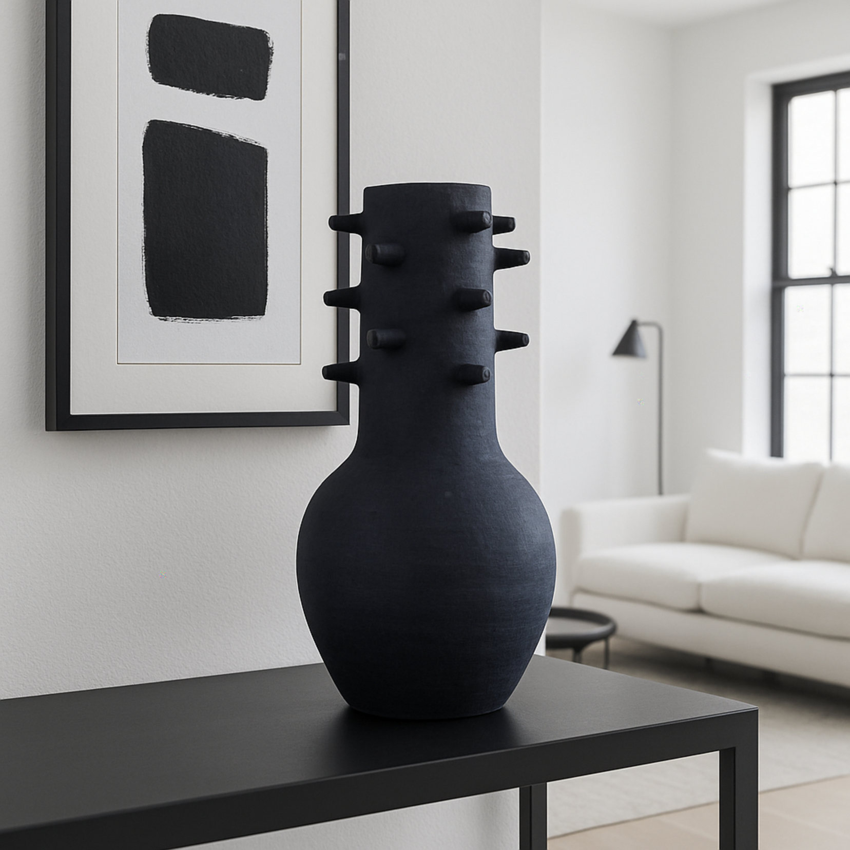 Spicula black textured vase from Love Hohm on a black table in a modern living room with abstract art and a white sofa.