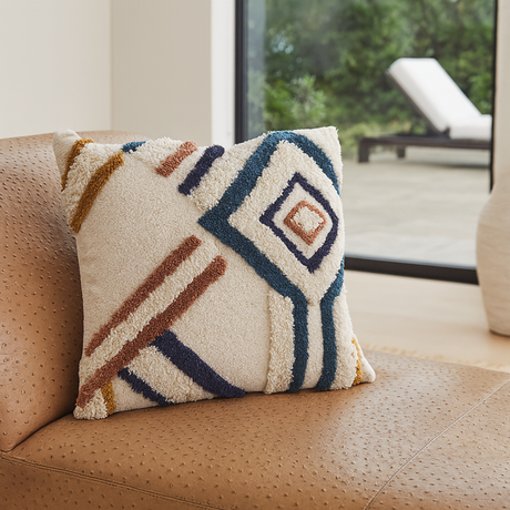 Stillwater decorative accent pillow from Love Hohm with geometric pattern on a brown ostrich chaise lounge