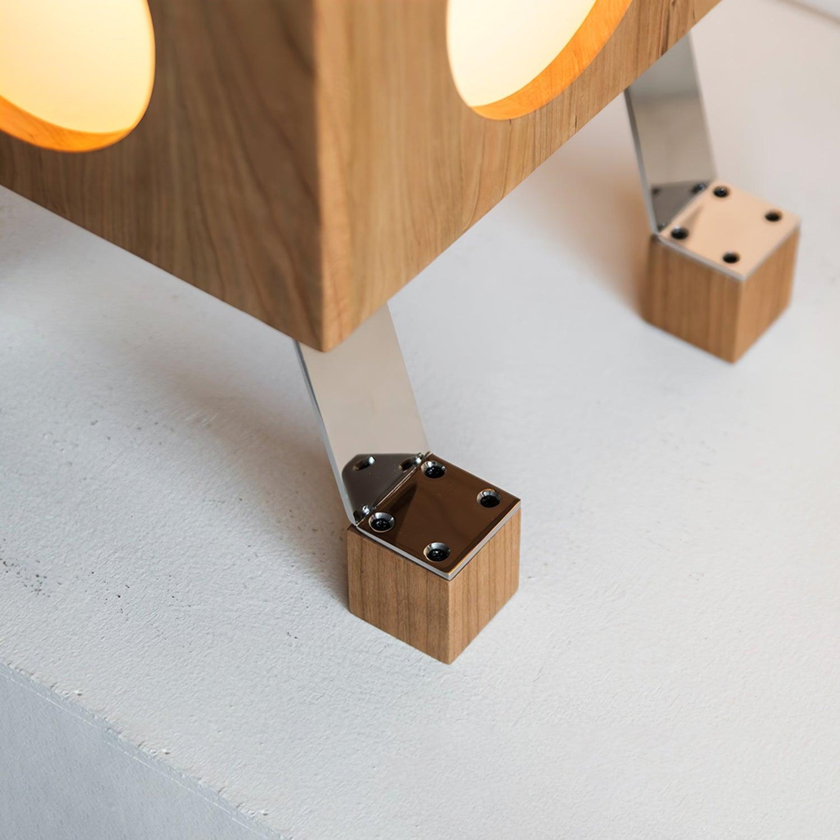 Torii floor lamp from Love hohm close-up of a wooden table leg with metal bracket on a light gray surface