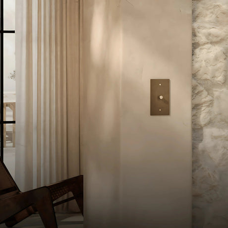 Verge brass dimmer by Love Hohm on a neutral wall next to a stone wall