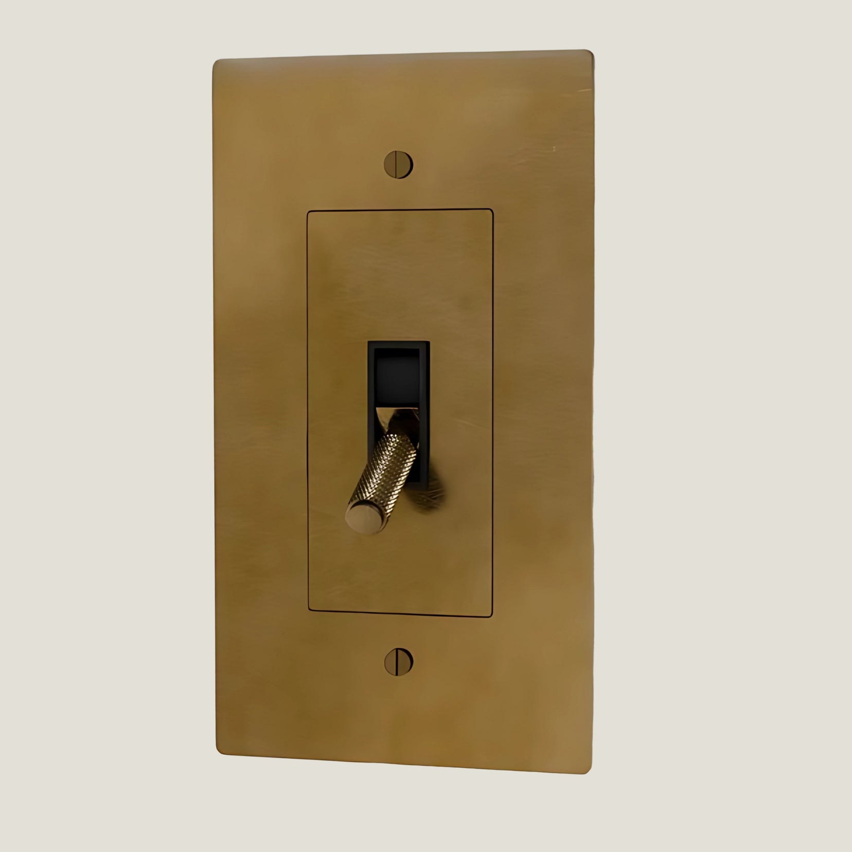 Verge brass toggle from Love Hohm with a black toggle switch on a beige background