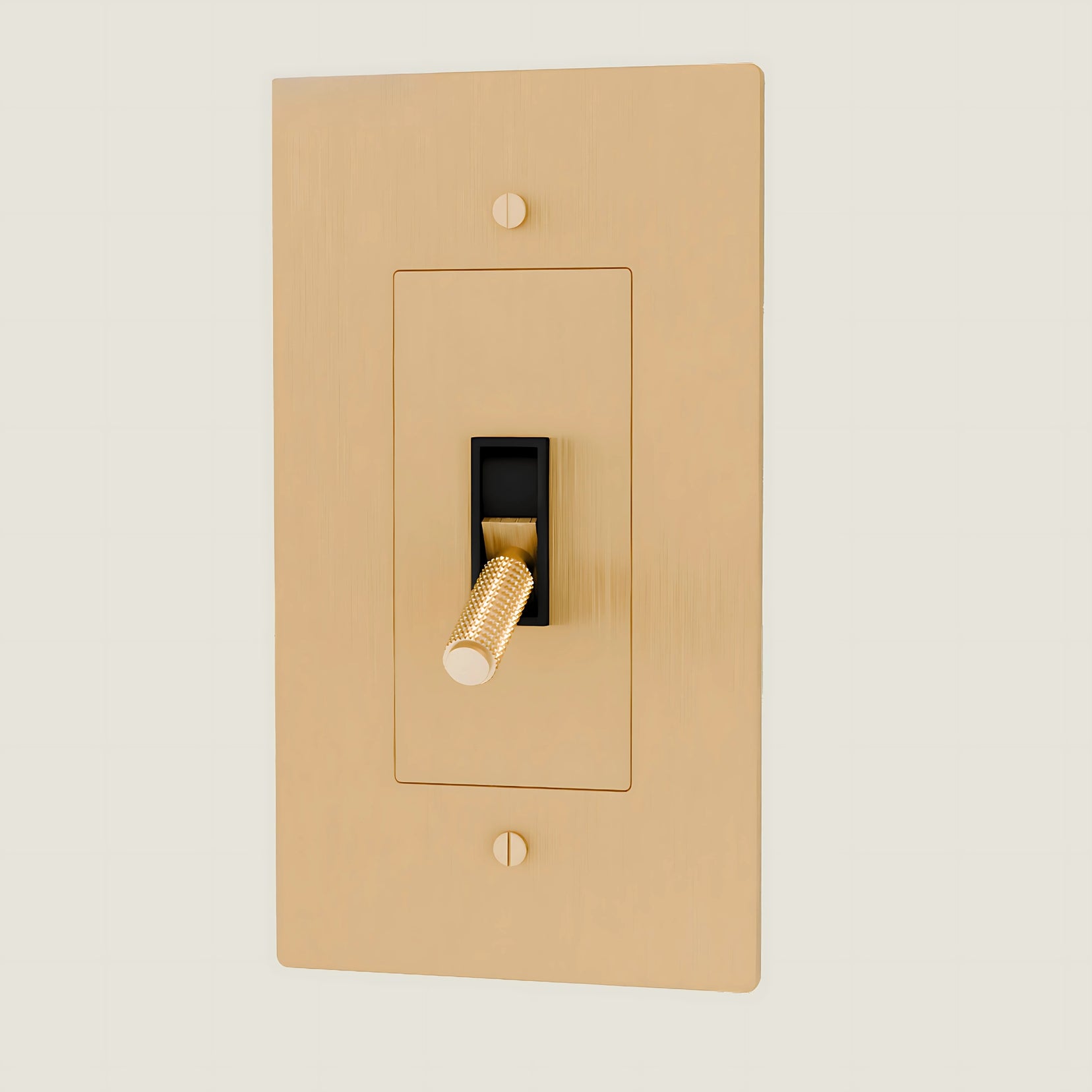 Verge brass toggle from Love Hohm with a black rocker on a beige background
